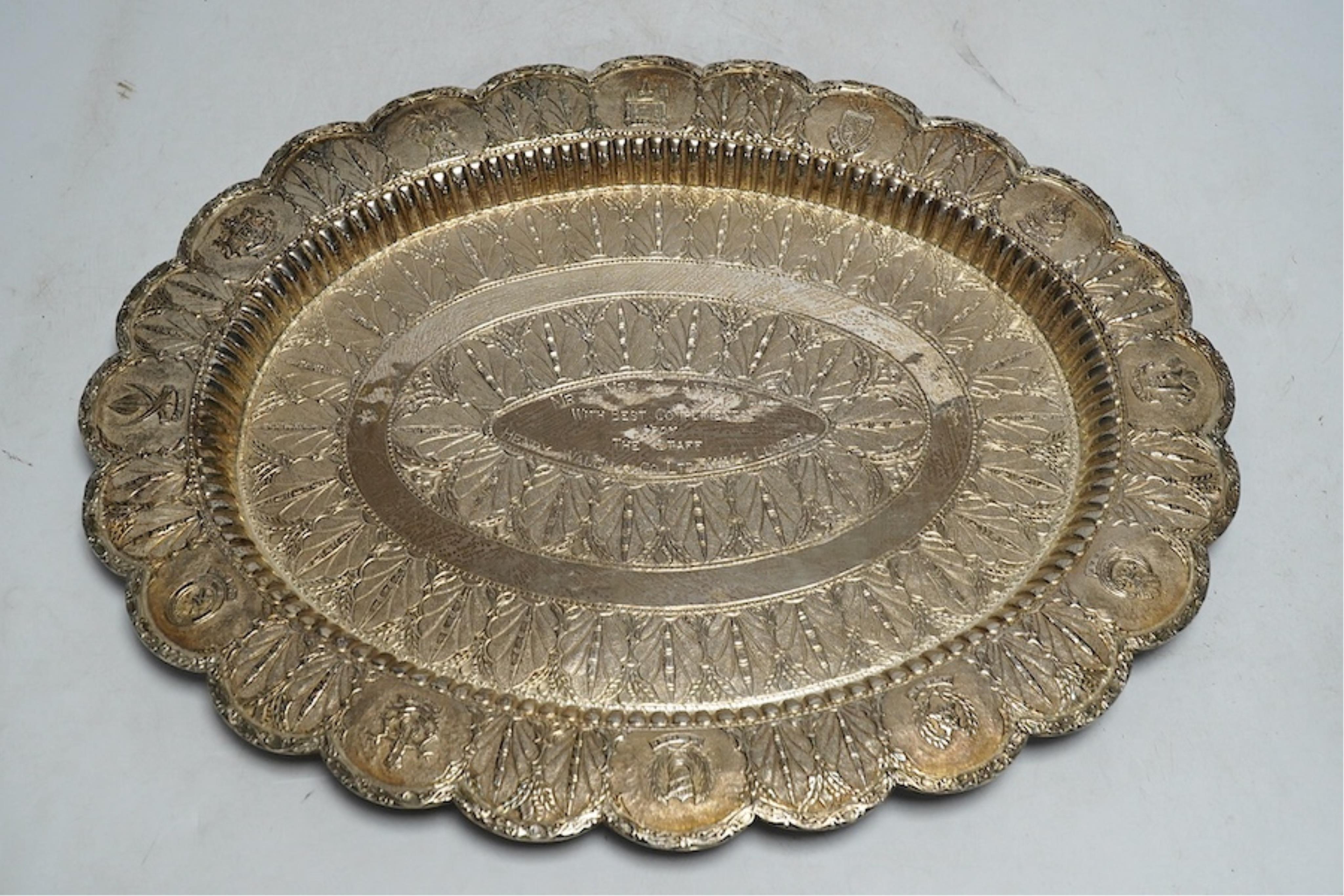 An Indonesian white metal oval dish, embossed and chased with the coats of arms of regions of Indonesia and Singapore, with a central leaf border and inscription, 38.5cm wide, 648g. Condition - good